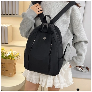 Detail of a lightweight black nylon backpack with metal logo on casual grey sweatshirt