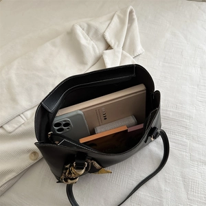 Elegant black leather tote bag with white stitching and decorative silk scarf detail