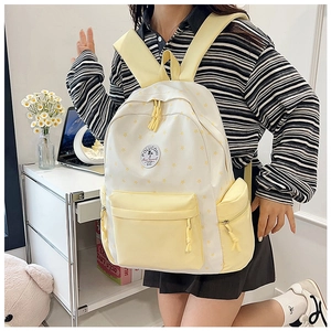 Detail of yellow and white school backpack with star patterns and Poluconi logo patch
