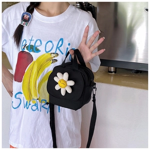 Détail d'un mini sac bandoulière en toile noire avec un ornement de fleur 3D souriante