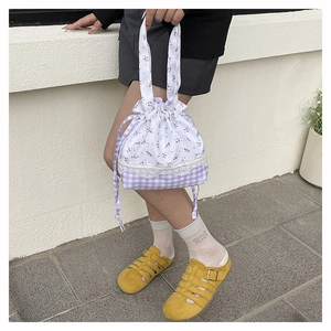 Detailed shot of purple plaid and floral bucket bag with white lace trim and drawstring