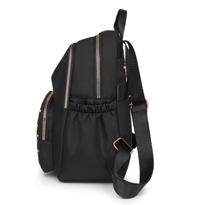 Black nylon backpack for women with multiple layers and golden zippers on white background