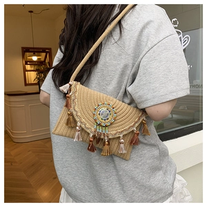 Close-up of bohemian straw envelope bag with colorful tassels and beaded mandala disk