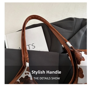 Detail of faux fur cow print handbag with brown leather handle and gold chain strap