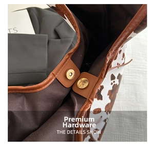 Detail of vintage gold magnetic buckle on cow print tote with brown leather trim