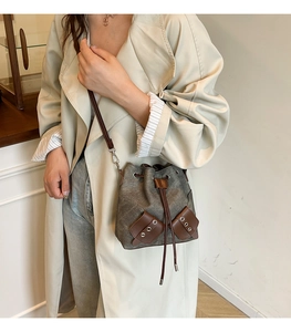 Retro canvas drawstring bucket bag with leather accents shown on a model in trench coat