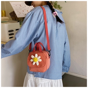 Détail du sac bandoulière en toile orange avec fleur de soleil 3D et anses rouges