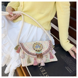 Detail of bohemian straw bag featuring colorful wave embroidery and vibrant hanging tassels