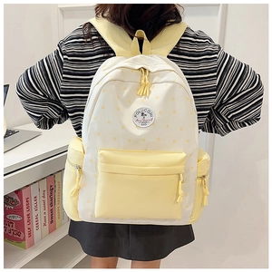 School backpack in creamy yellow with star prints shown in a student study setting