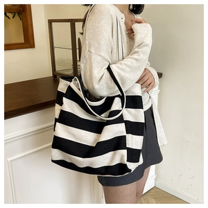 Detail of a large capacity black and white striped canvas tote bag worn on a shoulder