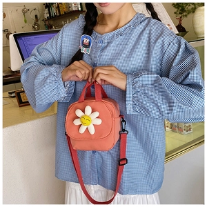 Détail du mini sac à bandoulière en toile rose avec marguerite 3D et lanières rouges
