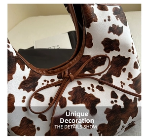 Close-up of vintage cow print shoulder bag with brown leather trim and bow detail