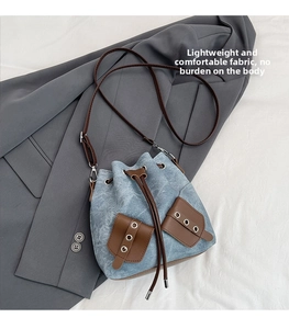 Detail of light blue denim bucket bag with brown synthetic leather drawstring and pockets