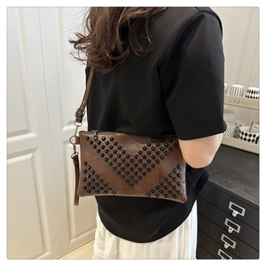 Detail of dark brown leather crossbody bag featuring unique V-shaped black rivet studs