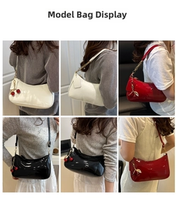 Detail of glossy patent leather shoulder bags in black, white and burgundy with cherry charms