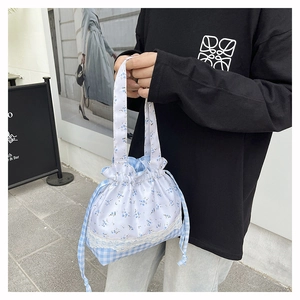 Detail of floral drawstring bucket bag with blue lace and plaid patchwork design