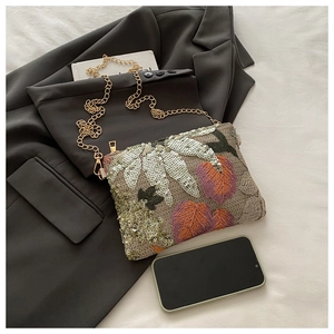 Detailed view of sequins and floral embroidery on a chic crossbody bag with gold chain