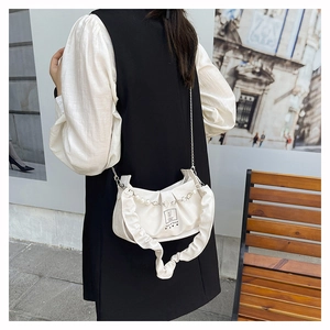Détail du sac nuage plissé blanc avec chaîne argentée et pendentif cœur en perle