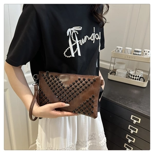 Brown envelope clutch bag with black pyramid studs in V-shape and wristlet strap