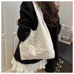 Detail view of white lace tote bag with delicate daisy embroidery on sheer mesh fabric