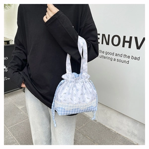 Detail of floral and checkered drawstring tote with delicate lace trimming and blue handles