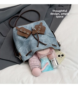 Blue denim bucket bag showing large interior capacity with a phone and umbrella
