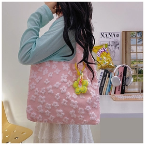 Detail of pink lace tote bag featuring white floral embroidery and a yellow flower charm