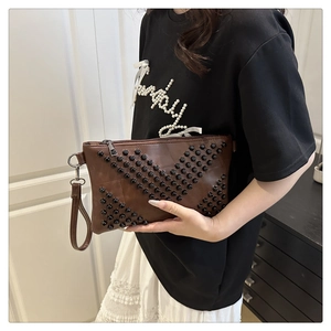 Detail of dark brown faux leather clutch with black studded geometric punk pattern
