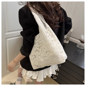 Detailed view of white floral lace embroidery on a lightweight mesh tote shoulder bag
