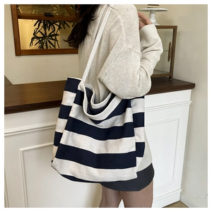 Detail view of large canvas striped tote bag worn over the shoulder in a casual setting