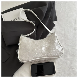 Gros plan du sac à main en dentelle blanche avec paillettes sur lin texturé et blazer