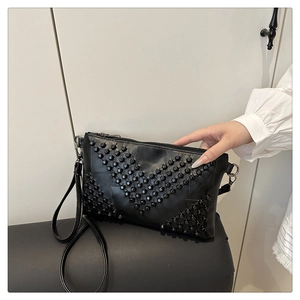Close-up of black square bag featuring dense rivet detailing and sleek metal zipper