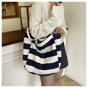 Detail of wide handles and navy striped canvas texture on a large tote bag