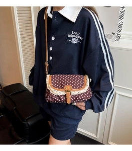 Dettaglio borsa a tracolla marrone a pois con bordo in pizzo beige e fibbia in pelle