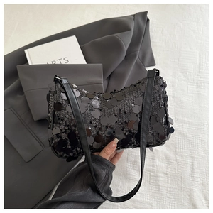 Détail d'un sac hobo noir à paillettes avec texture scintillante et fine bandoulière