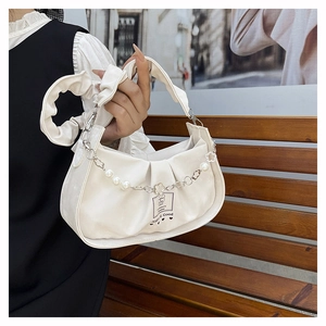 Détail du sac plissé blanc avec chaîne de perles fleurs et étiquette logo ours