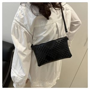 Detail of black studded envelope crossbody bag featuring punk style metal rivets on leather