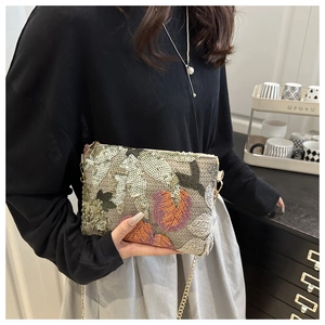 Detailed shot of sequin leaf embroidery and golden chain strap on a rectangular clutch bag