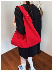 Detailed back view of a large red canvas tote bag showing its size and fit on a person