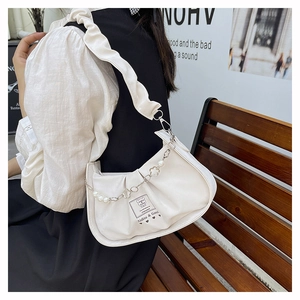 Détail du sac nuage plissé blanc avec perles et chaîne florale argentée sur la bandoulière