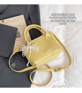 Detail of yellow lychee pattern handbag with pearl lace bow and adjustable strap