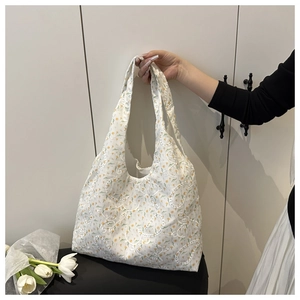 Detail of floral lace embroidery and paisley patterns on a white canvas tote bag