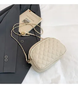 Detail of off-white quilted crossbody bag with metal chain strap and leather texture