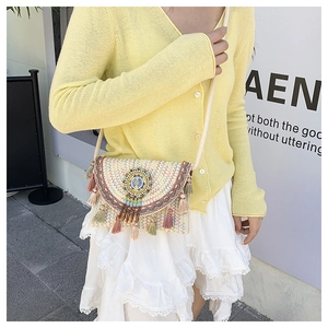 Detail of bohemian straw bag featuring colorful beaded charms and vibrant tassels