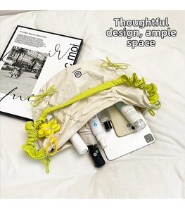 Ampia borsa tote plissettata bianco sporco con coulisse verde neon e oggetti quotidiani