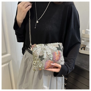 Detail of sequins embroidery and gold chain strap on an elegant evening clutch bag