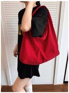 Detail showing the red canvas tote bag texture and large capacity on model shoulder