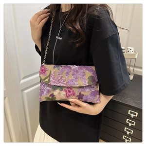 Dettaglio del ricamo floreale con paillettes su borsa in tessuto beige e catena