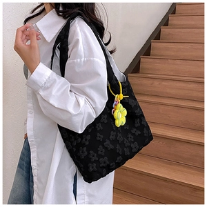 Close-up of black floral lace tote bag with a vibrant yellow flower charm on model