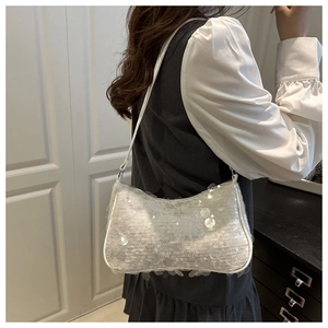 Détail d'un sac sous le bras à paillettes argentées avec bandoulière blanche et zip